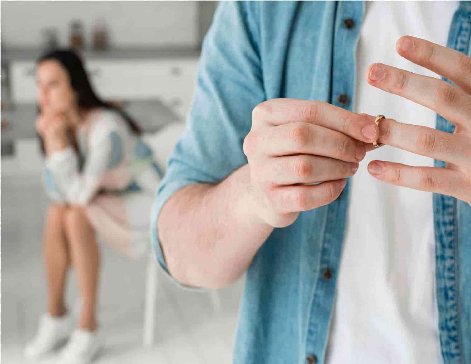 Mężczyzna zdejmuje obrączkę, w tle zmartwiona kobieta: świadek w sprawie rozwodowej w Białymstoku